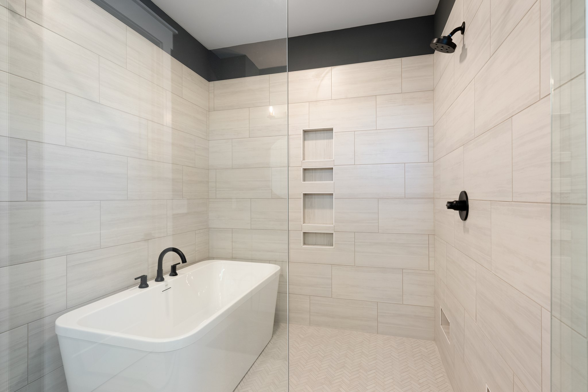 Close-up of a modern soaking tub and tiled shower with black fixtures
