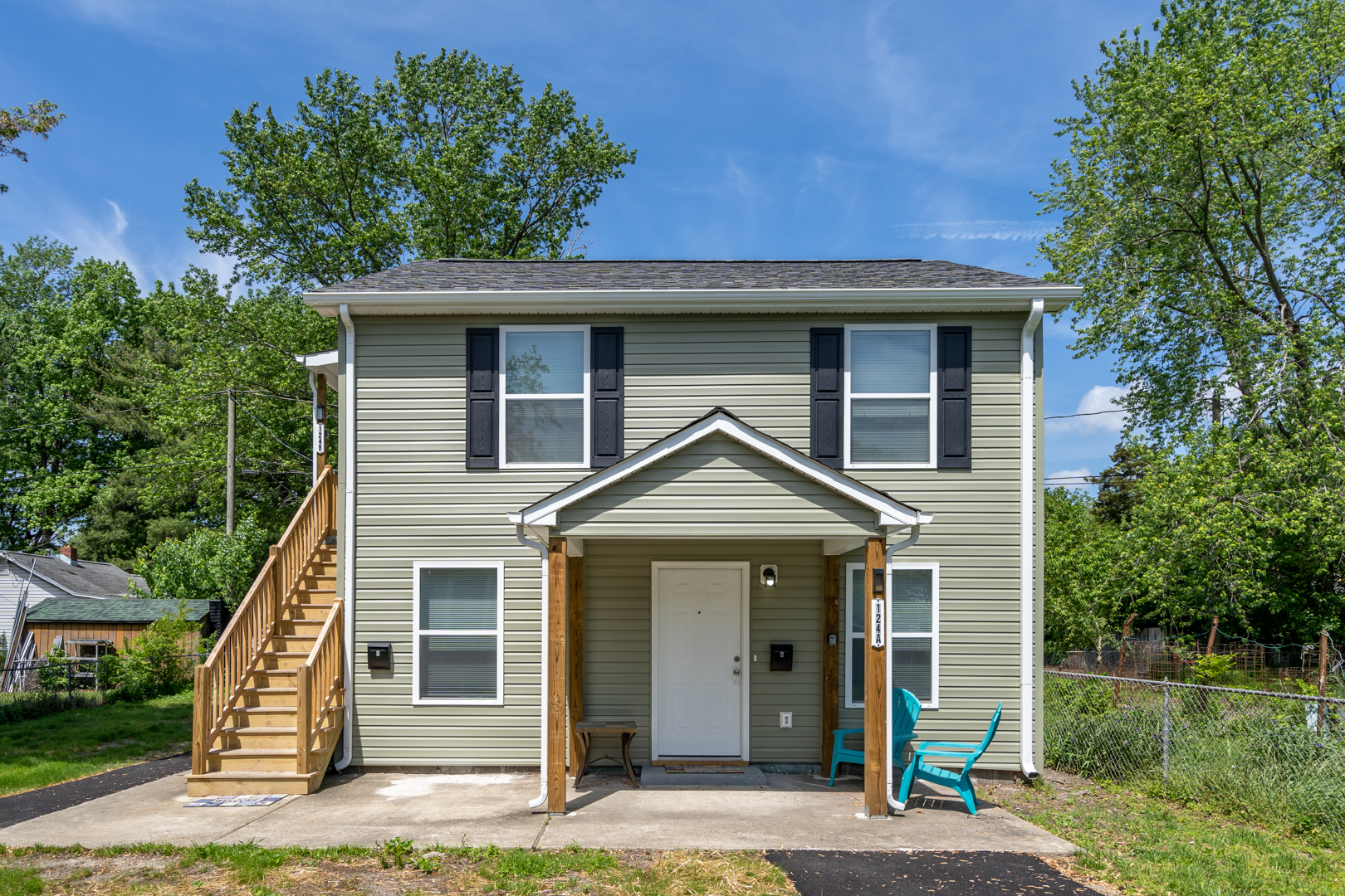 Front view of a modern two-story duplex with outdoor seating and a covered porch.