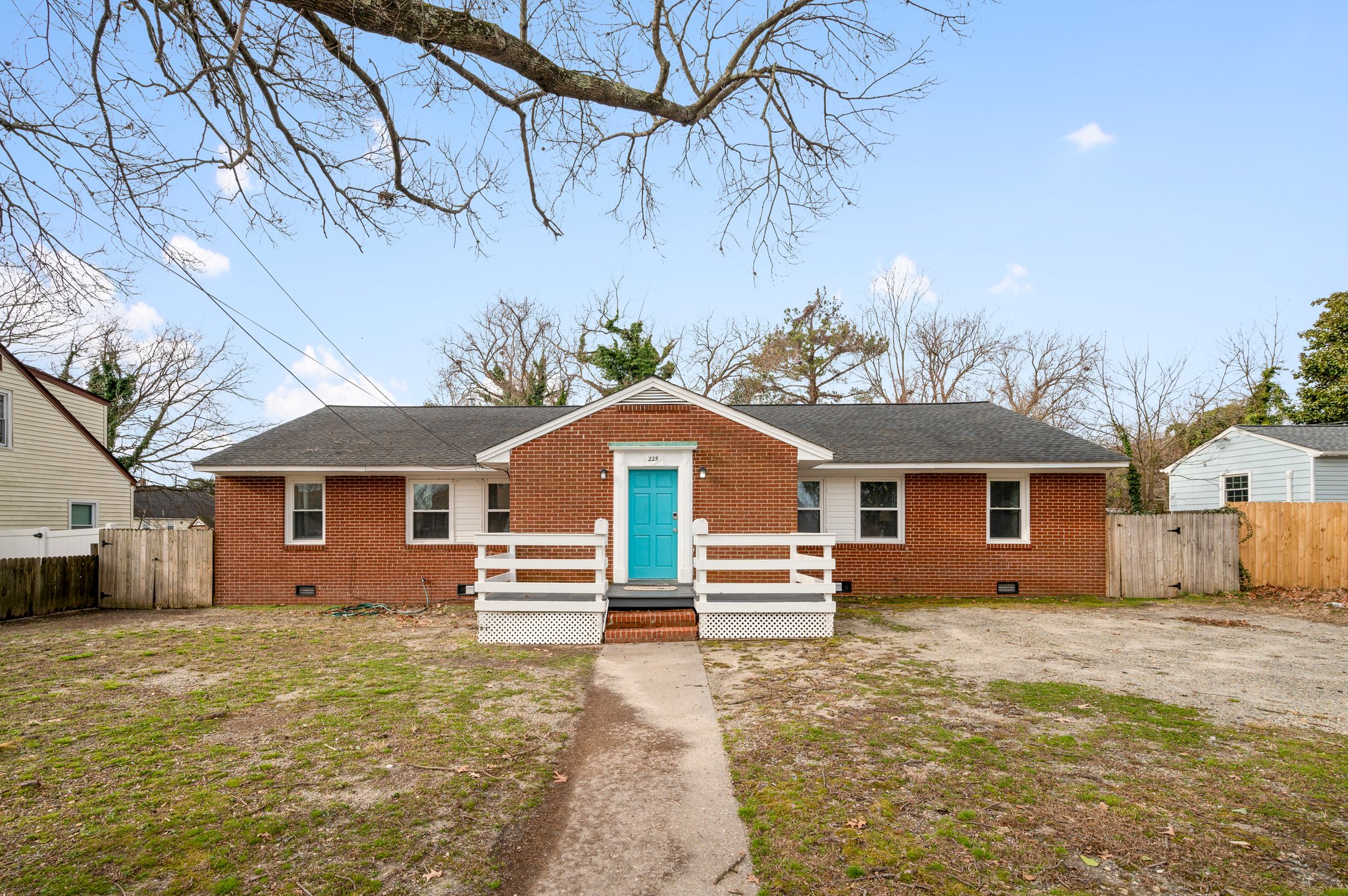 Front view of a brick duplex with blue door and white porch railing.